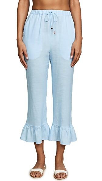 Model wearing ruffled linen pants with drawstring front and side pockets — eco-friendly beach to bar resortwear made from 100% linen