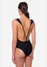 Model wearing The Plunge One Piece Swimsuit with deep V neckline, ruffle detail, and adjustable straps — designer swimwear made for bold beach moments